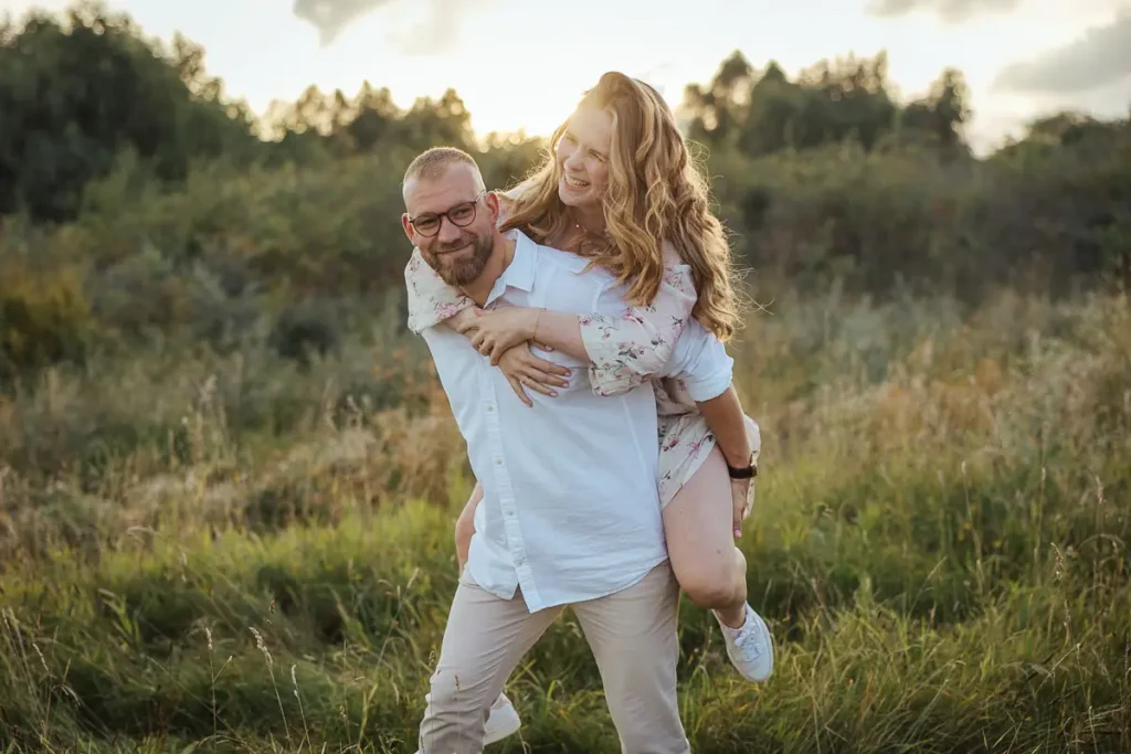 Frau auf der Schulter des Mannes in Hooksiel bei Sonnenuntergang
